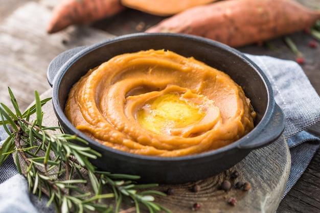 Pittige puree van zoete aardappel of zoete aardappelpuree met rozemarijn in een steelpannetje op tafel