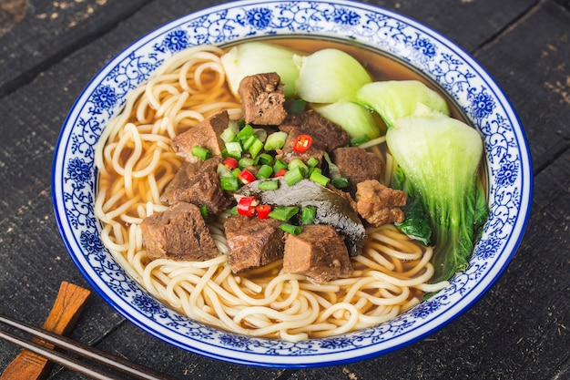 Pittige rode soep beef noodle in een kom op houten tafel