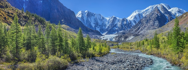 Pittoresk bergdal met rivier en besneeuwde bergtoppen