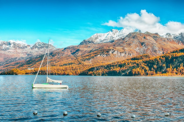 Pittoresk herfstgezicht op Sils Silsersee met klein wit jacht