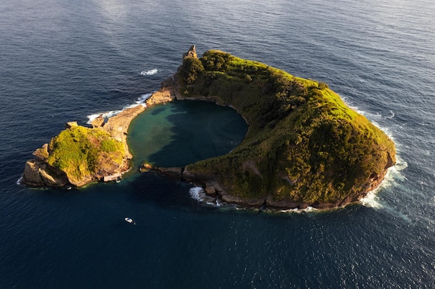 Pittoresk vulkanisch eilandje in golvende oceaan op zonnige dag