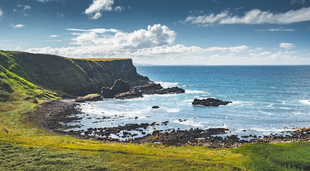 Pittoreske baai van Noord-Ierland met groen gras bedekt land naast het oceaanwater verbazingwekkende zee