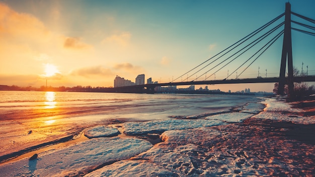 Pivnichnyi Bridge silhouette over half frozen Dnipro river