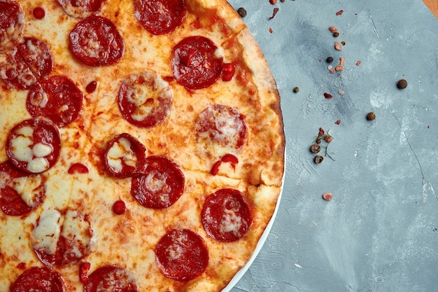 Pizza baked in a wood oven with melted cheese and chorizo salami on a gray