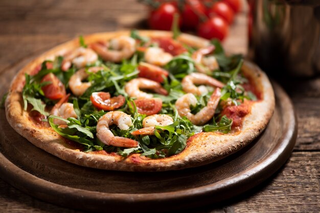 Pizza bedekt met roquette en garnalen op houten tafel close-up