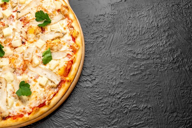 Pizza on a black background on a tomato base with mozzarella, grilled chicken