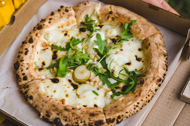 Pizza in a box in the hands of a courier, food delivery