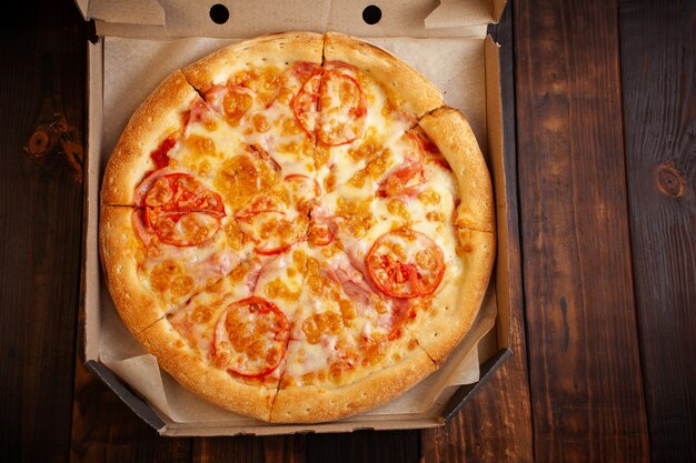 Pizza in a box on a wooden table