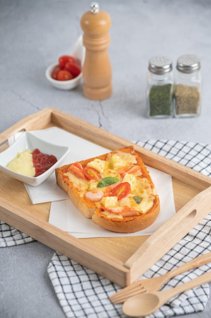 Photo pizza bread topped with shrimp crab sticks tomatoes cheese in a wooden tray