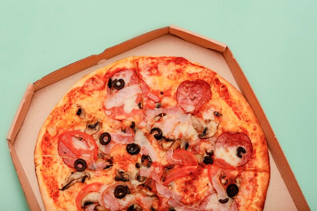 Pizza in brown corrugated cardboard take-out box on colored table. round, pizza