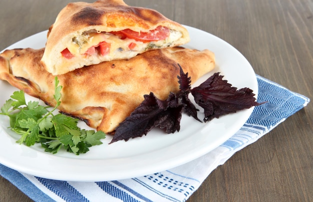 Pizza calzone on plate on napkin on wooden table