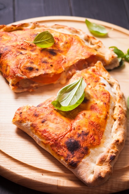 Pizza calzone with basil leaves close up