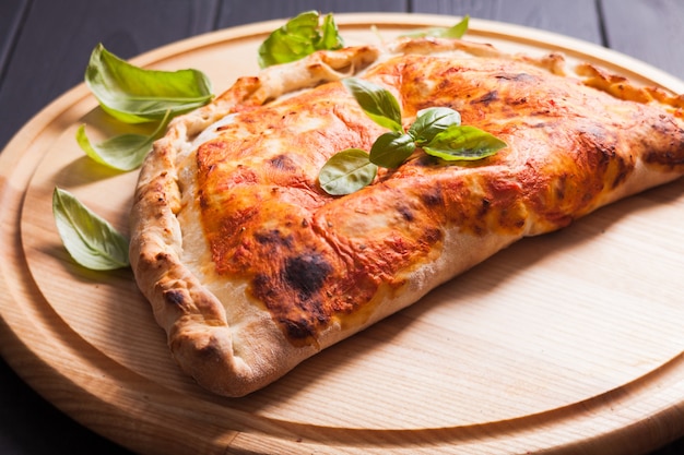 Pizza calzone con foglie di basilico primo piano