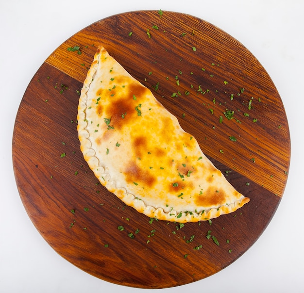 pizza calzone with red and white sauce on a wooden board