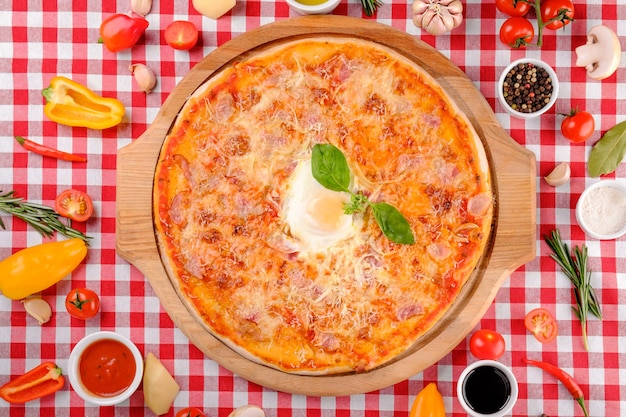 Pizza Carbonara met spek, ei, parmezaanse kaas, verse basilicum en tomatensaus op een houten bord