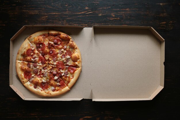 Pizza in a cardboard box against a dark background View from above Pizza delivery