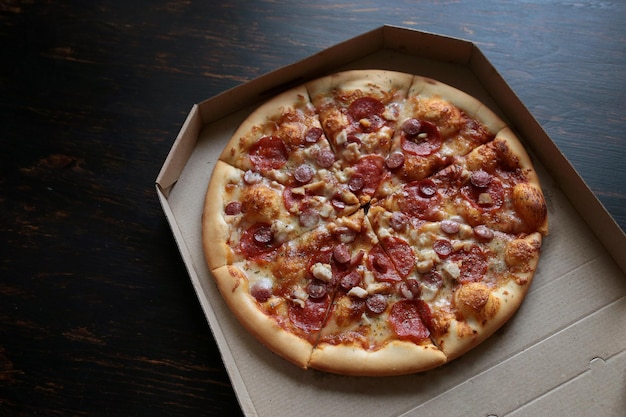 어두운 배경에 있는 골판지 상자에 있는 피자 피자 배달 위에서 보기