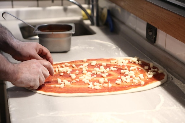 Pizza chef put sauce on base in a commercial kitchen