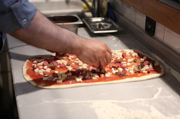 Pizza chef put sauce on base in a commercial kitchen