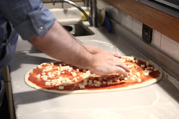 Pizza chef put sauce on base in a commercial kitchen