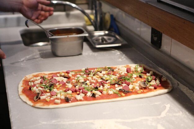 Pizza chef put sauce on base in a commercial kitchen