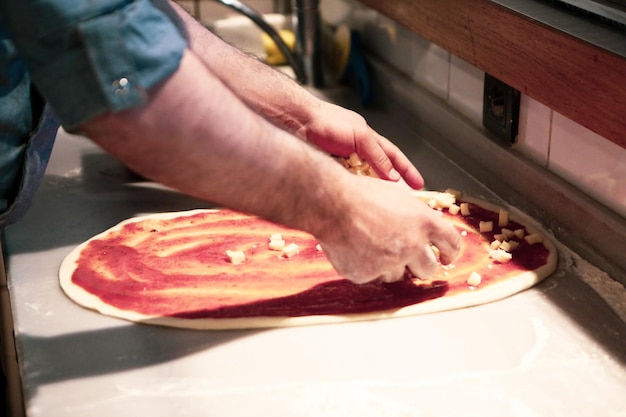 Pizza chef put sauce on base in a commercial kitchen