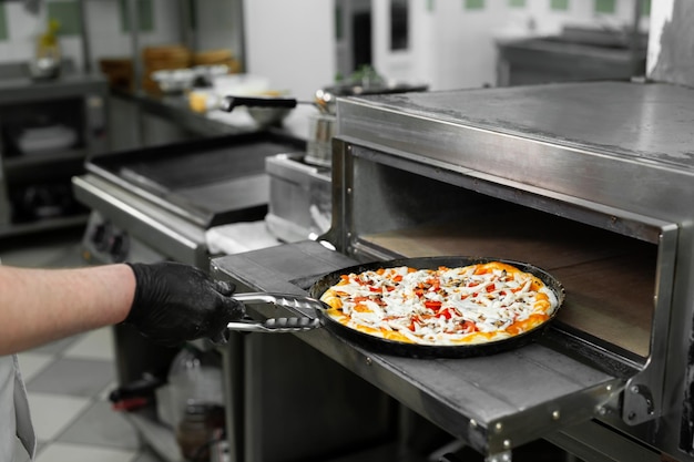 Pizza chef puts pizza in the oven to bake in the oven in the\
restaurant kitchen