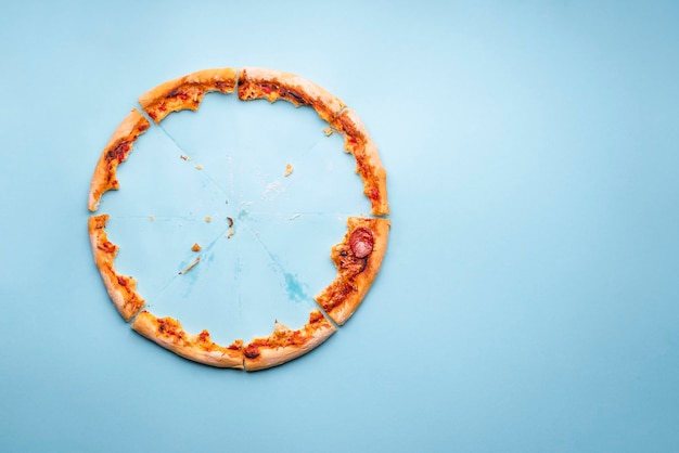 Photo pizza crust leftovers on blue paper background top view