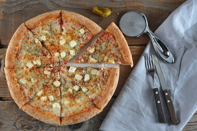 Pizza cut into pieces with cheese and tomatoes and hot pepper