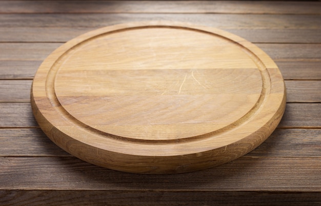 Pizza cutting board at rustic wooden table plank background, front view