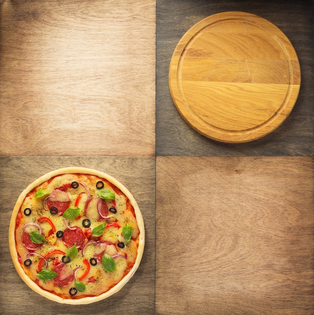 Photo pizza and cutting board at wooden table, top view