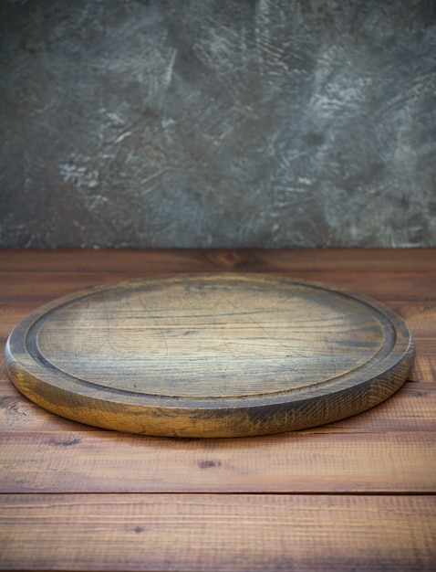 Photo pizza cutting board at wooden table, with wall background texture