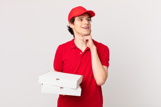 Pizza deliver man smiling happily and daydreaming or doubting