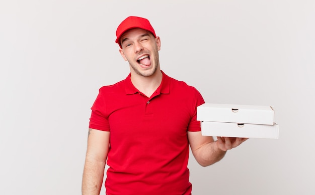 Pizza deliver man with cheerful, carefree, rebellious attitude, joking and sticking tongue out, having fun