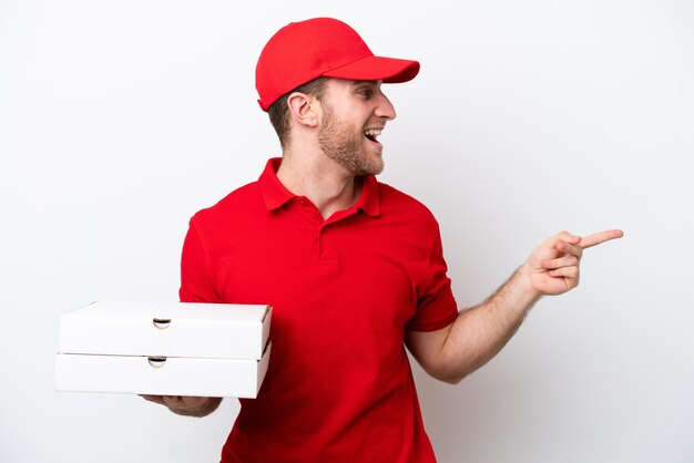 Pizza delivery caucasian man with work uniform picking up pizza boxes isolated on white background pointing finger to the side and presenting a product