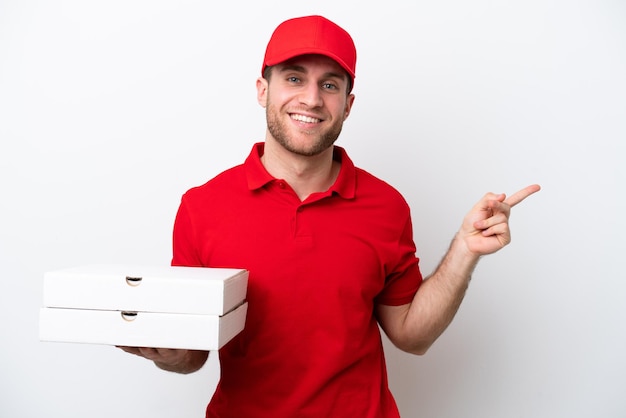 Pizza delivery caucasian man with work uniform picking up pizza boxes isolated on white background pointing finger to the side