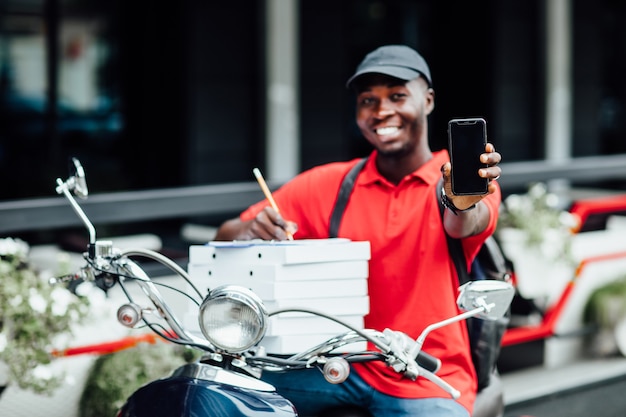 Pizza delivery man carries stack of boxes works on scooter fast food from restaurant for customers