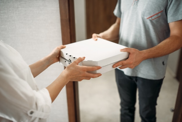 Pizza delivery man gives box to female client