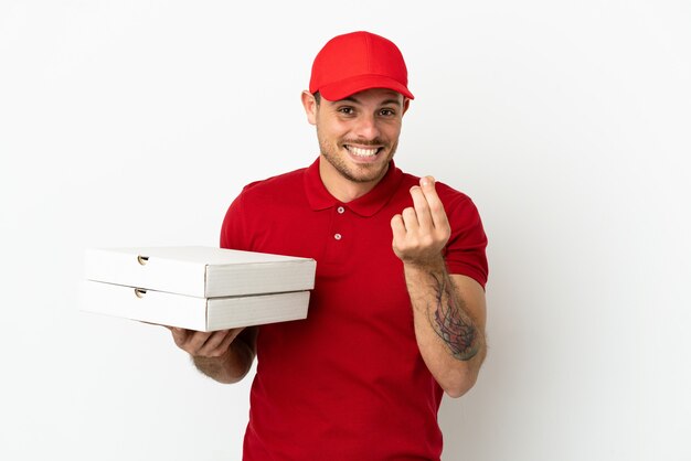 Pizza delivery man with work uniform picking up pizza boxes over isolated  white wall making money gesture