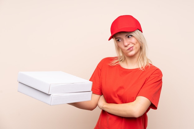 Pizza delivery Russian woman holding a pizza over isolated wall with sad expression