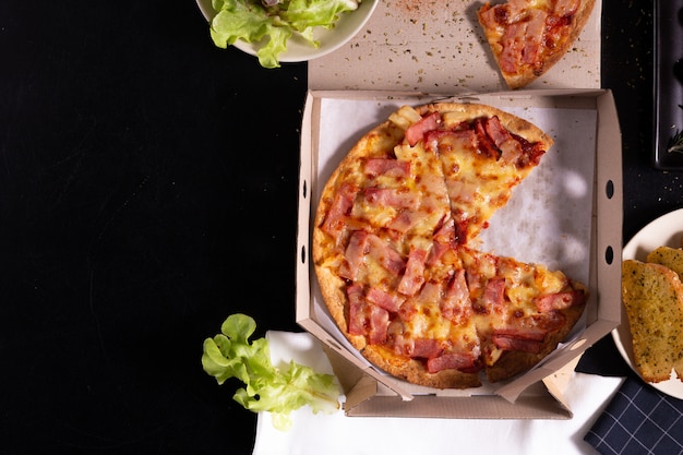 Pizza delivery service in a cardboard box with cheese garlic bread