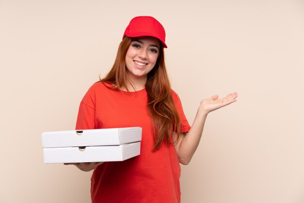 Pizza delivery teenager girl holding a pizza holding copyspace imaginary on the palm