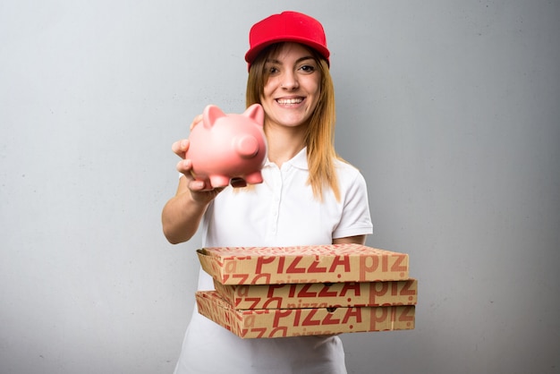 Pizza delivery woman holding a piggybank on textured background