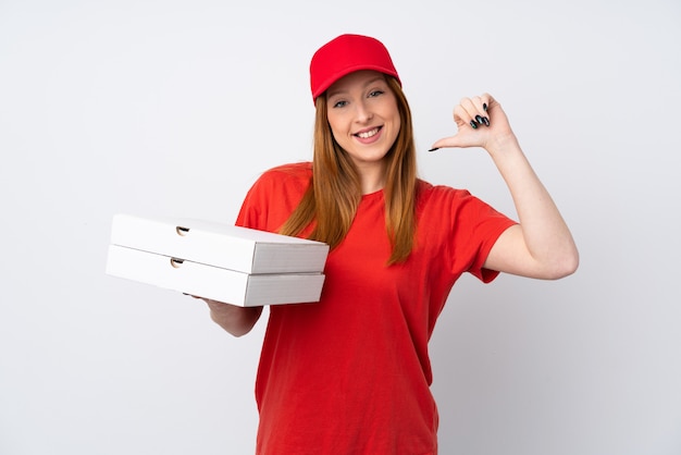 Pizza delivery woman holding a pizza over isolated pink wall proud and self-satisfied