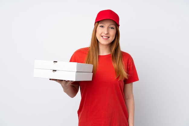 Pizza delivery woman holding a pizza over isolated pink wall smiling a lot