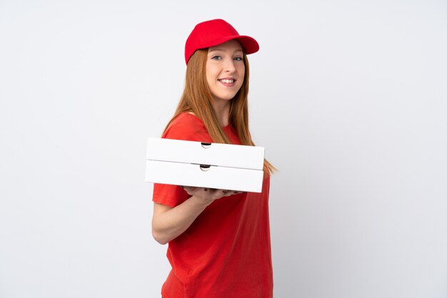 Pizza delivery woman holding a pizza over isolated pink wall smiling a lot