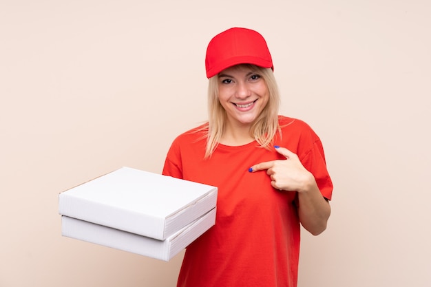 Pizza delivery woman holding a pizza over isolated wall with surprise facial expression