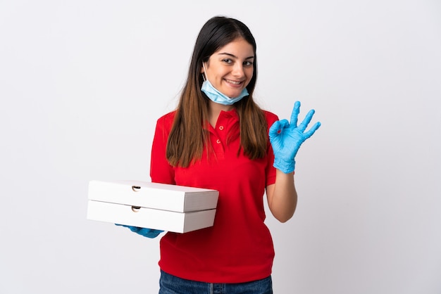 Женщина доставки пиццы, держа пиццу, изолированные на белом, показывая знак ОК с пальцами