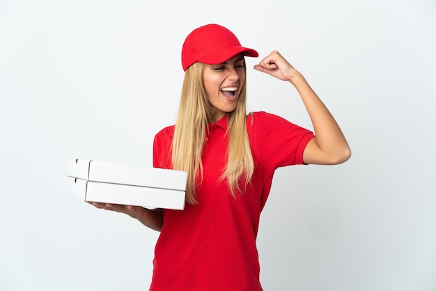 Pizza delivery woman holding a pizza isolated on white space celebrating a victory