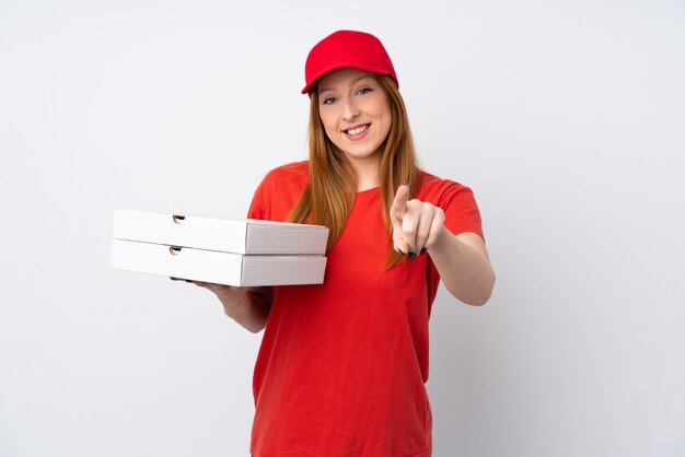 Pizza delivery woman holding a pizza over pink wall points finger at you with a confident expression